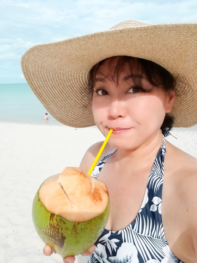 はじめてのリゾートホテルのプライベートビーチでココナッツジュースを飲む51歳
